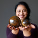 sheila of satin crystals holding a giant brown tiger iron spheres and a small tiger eye sphere