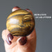 hand holding Tigers Eye with Hematite Sphere