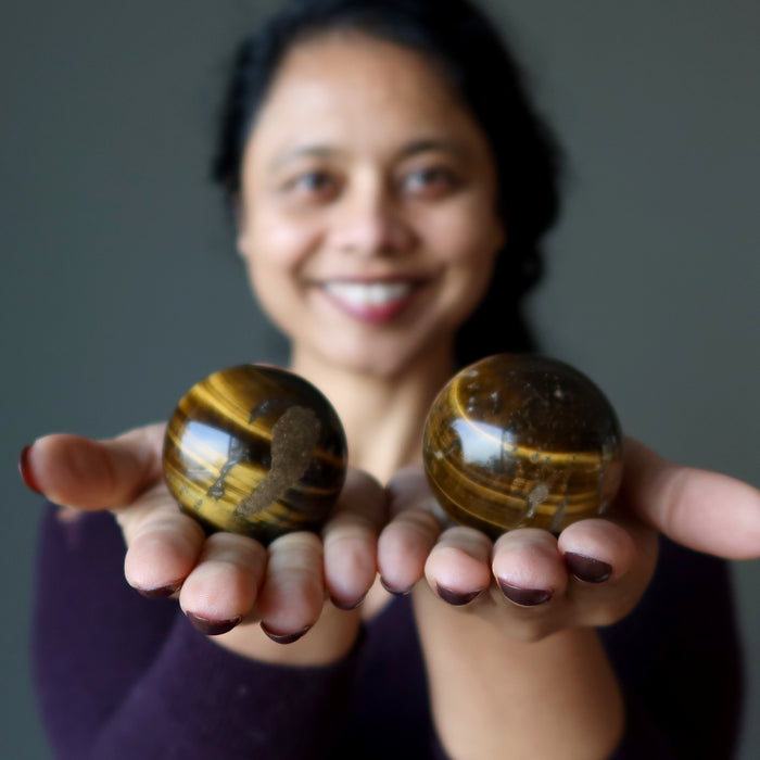 sheila of satin crystals holding 2 Den Muddy Earth Tigers Eye Spheres one on each hand
