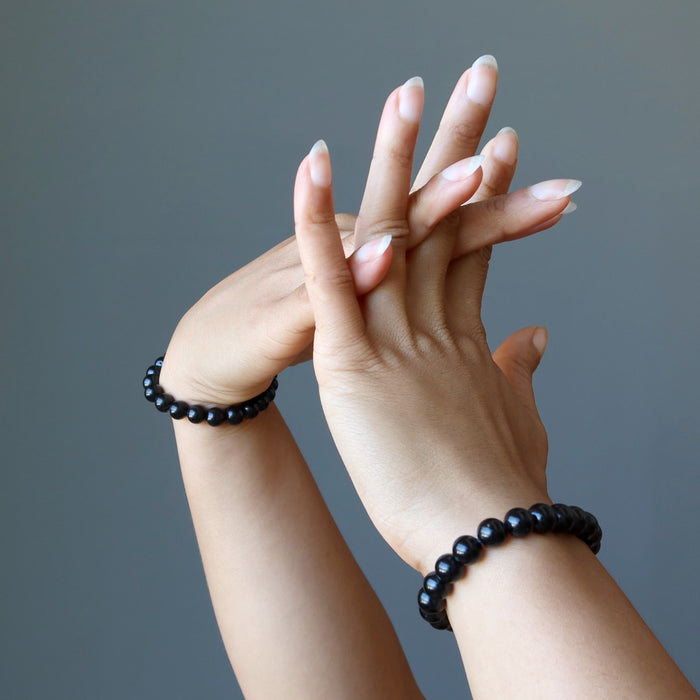 hands intertwined each wearing black tourmaline round stretch bracelets