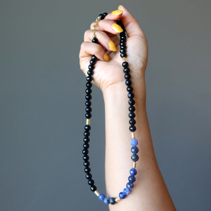 hand holding faceted black tourmaline and blue sodalite necklace