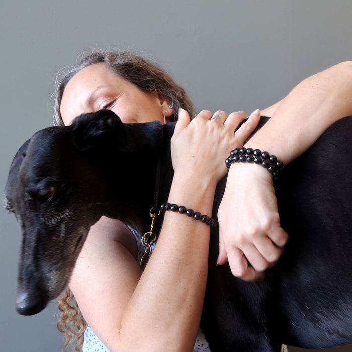 aleks of satin crystals wearing 3 faceted black tourmaline stretch bracelets hugging dorothy the greyhound dog