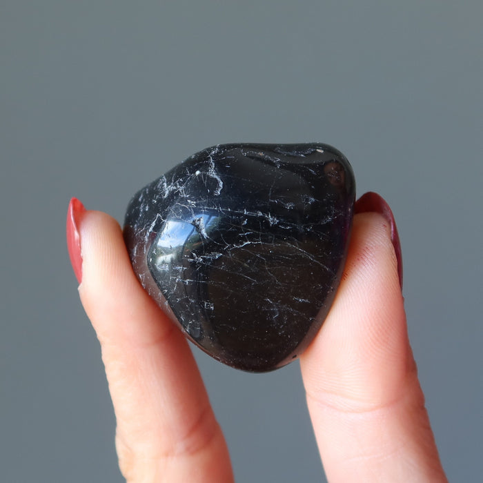 hand holding black tourmaline tumbled stone