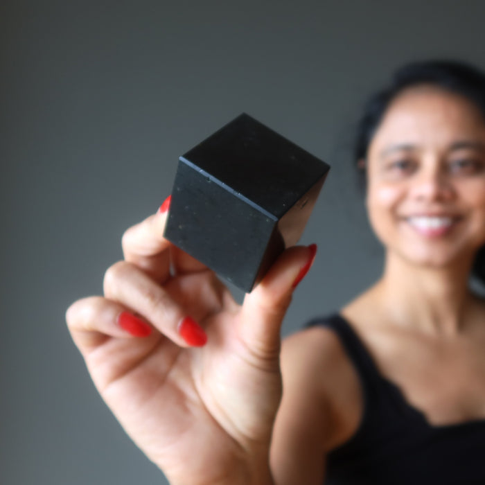 woman holding black tourmaline cube 