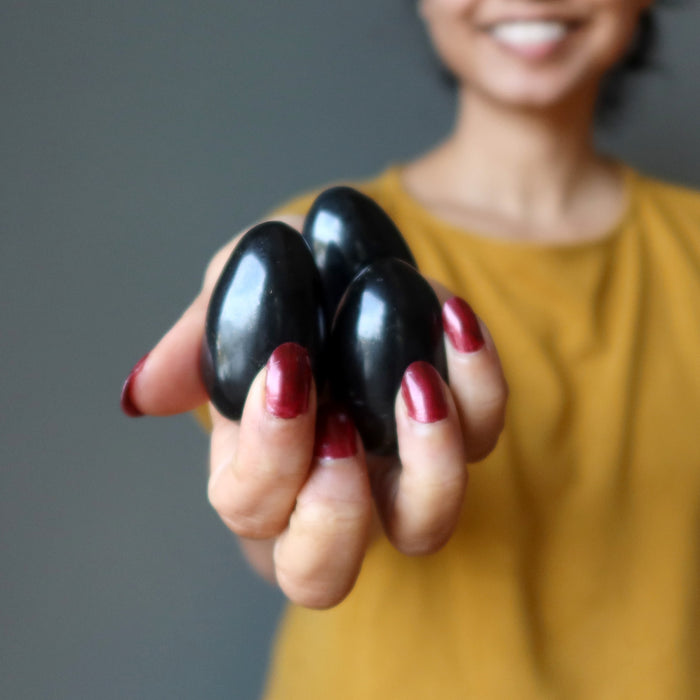 hand holding three black tourmaline eggs