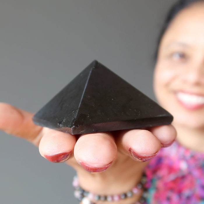 female holding black tourmaline pyramid