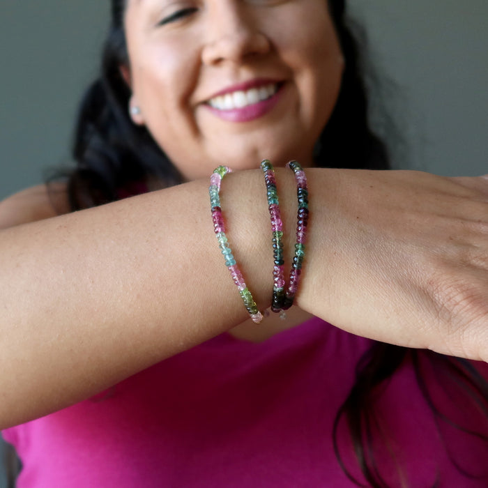 woman admiring faceted rainbow tourmaline bracelets