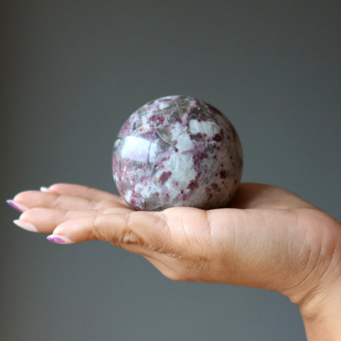 hand holding rubellite tourmaline sphere
