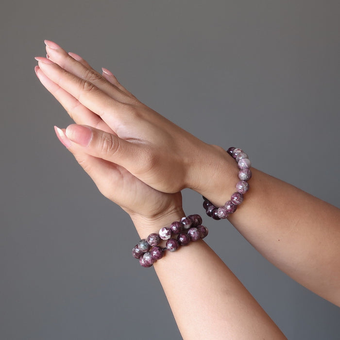 pair of hands in prayer pose wearing 3 Pink Tourmaline bracelets with lush raspberry tones in round smooth beads