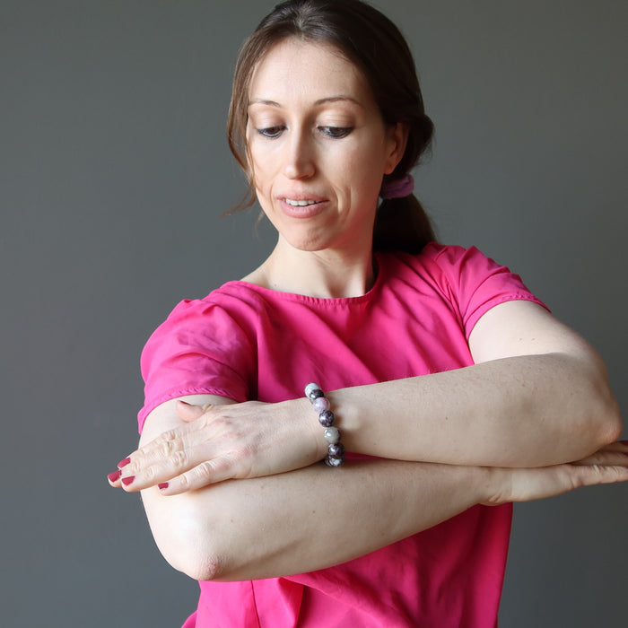A women crosses her arms to admire her pink tourmaline gemstone bracelet