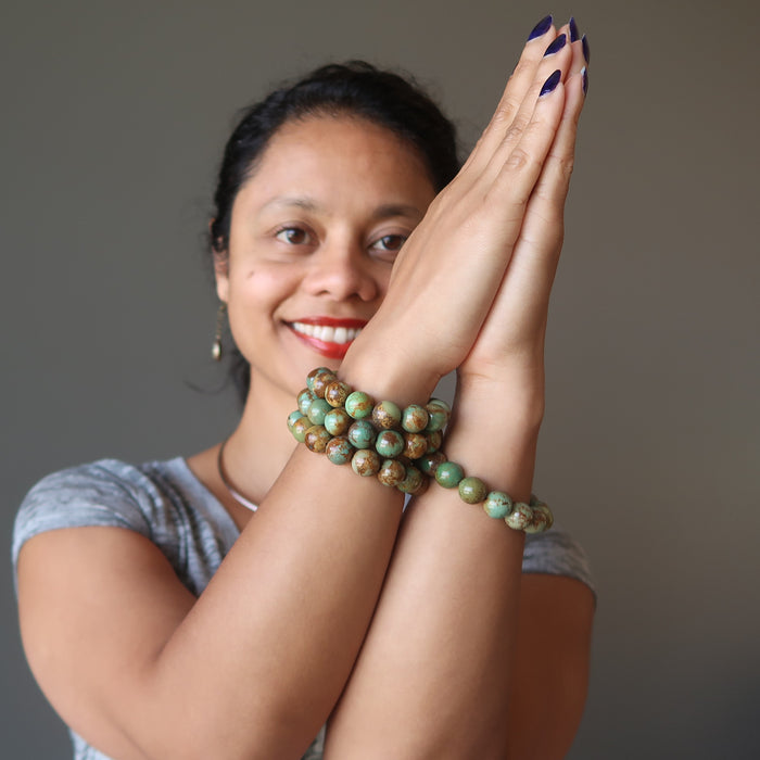 sheila of satin crystals with hands in prayer wearing green and brown turquoise jasper round beaded stretch bracelets