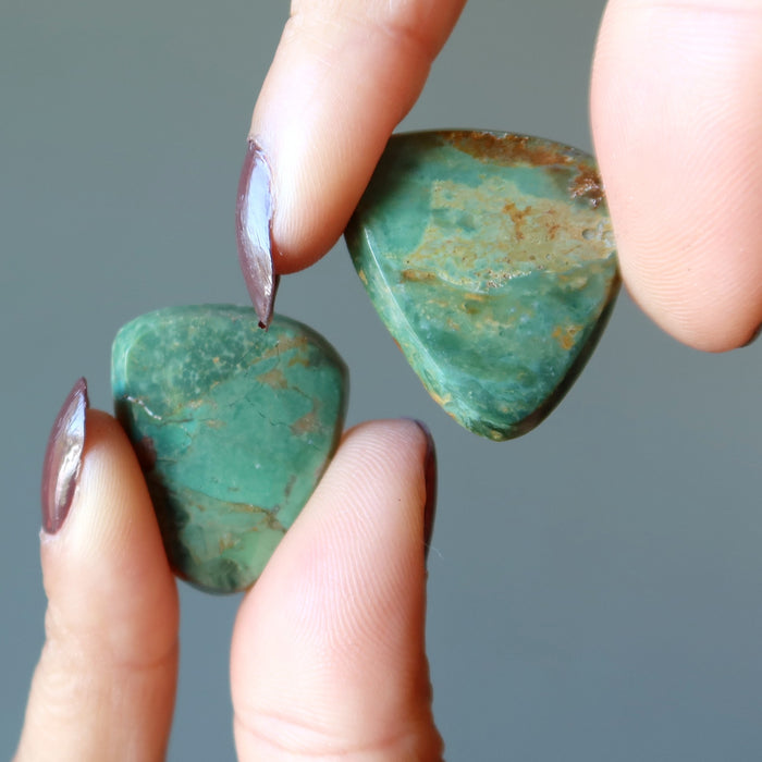 finger tips holding 2 Turquoise Polished Stones 