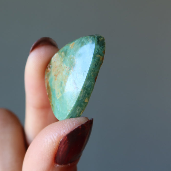 finger tips holding Turquoise Polished Stone 
