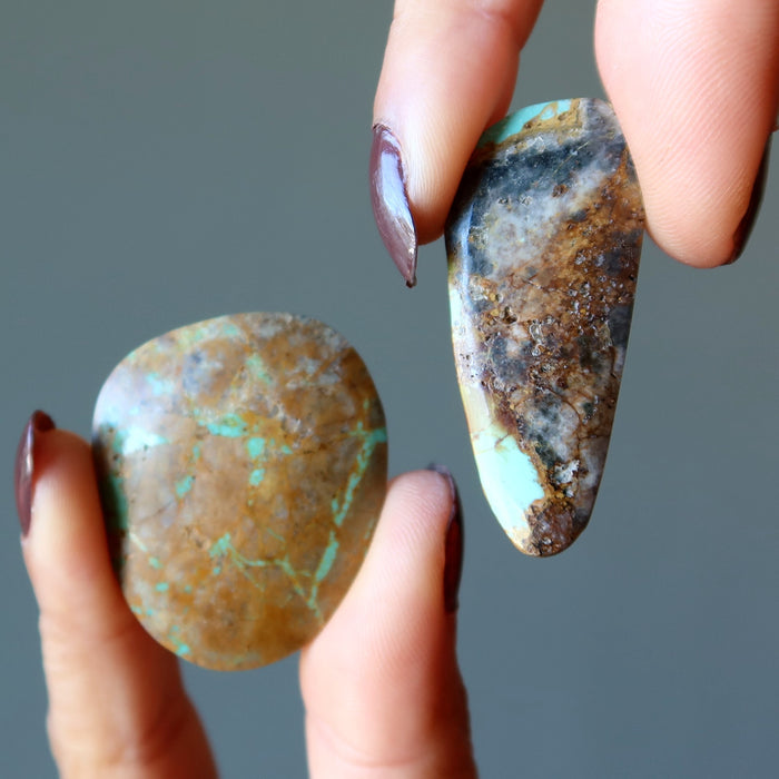 two hands holding 2 Turquoise Polished Stones