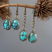 two pairs of Blue Oval Antiqued Leaf Turquoise Earrings hanging on the dry brown branch
