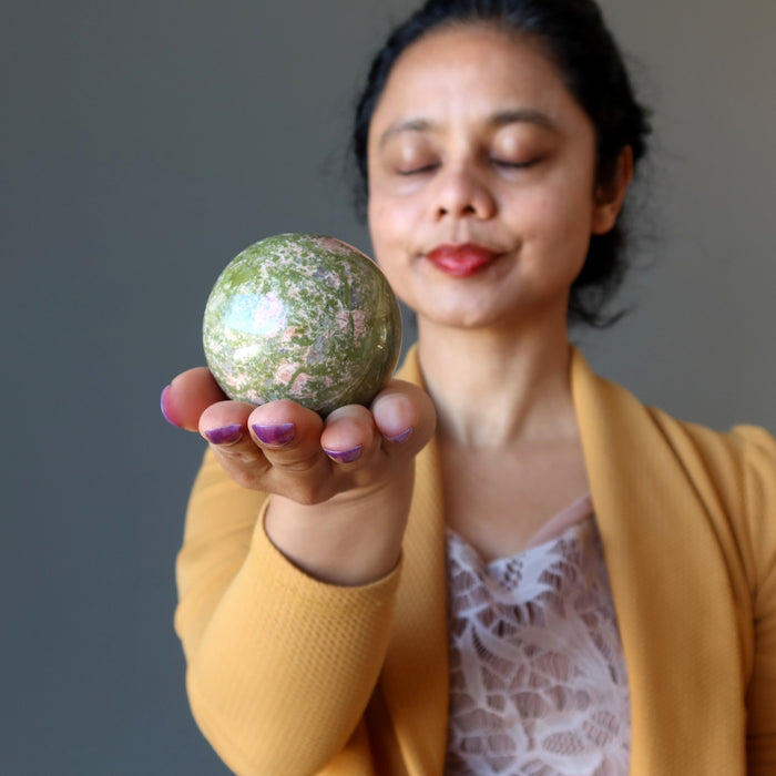 woman meditating with unakite sphere