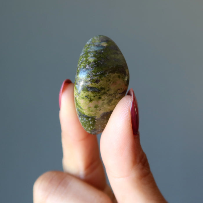 fingers holding a Unakite Tumbled Stone